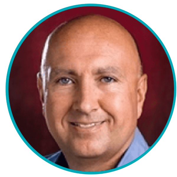Smiling bald man with blue eyes, wearing a blue shirt against a red background, circular border.